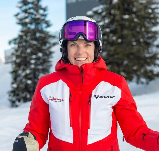 Skifahrerin in roter Jacke, die draußen lächelt
