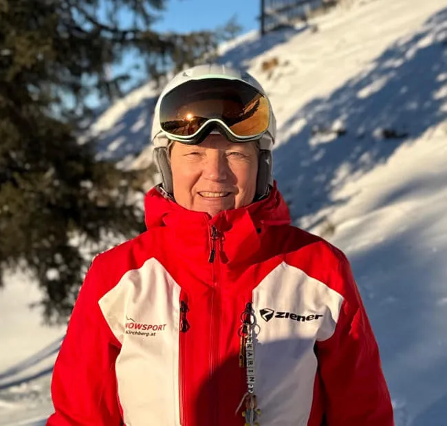 Person in Skiausrüstung lächelt auf verschneiter Piste