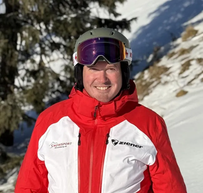 Mann mit Helm und roter Jacke im Schnee