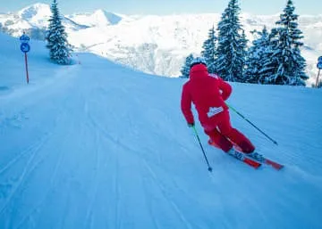Skifahrer in roter Kleidung auf einer Piste im Schnee