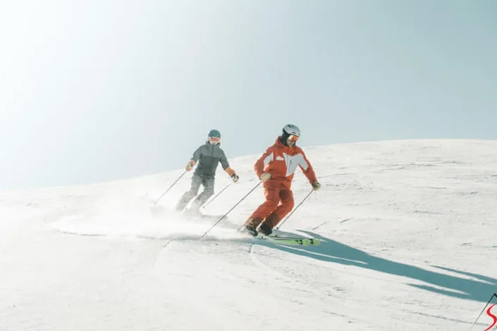 Zwei Skifahrer auf verschneiter Piste in Kirchberg