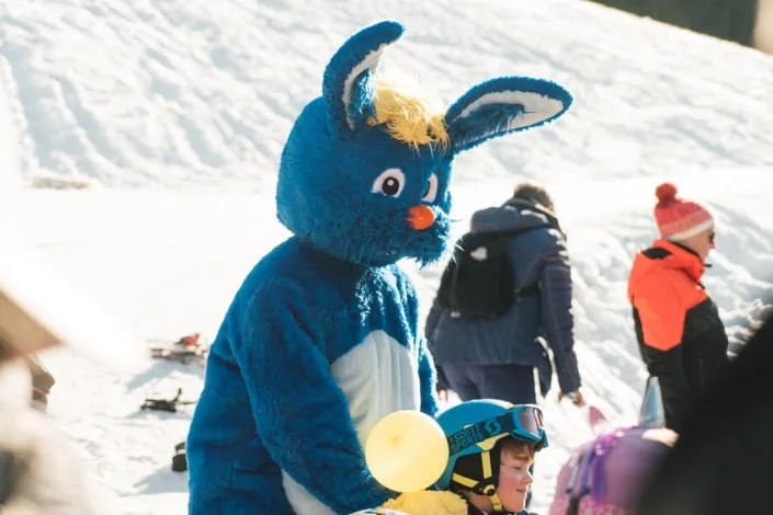 Blauer Hasenmaskottchen auf verschneitem Gelände