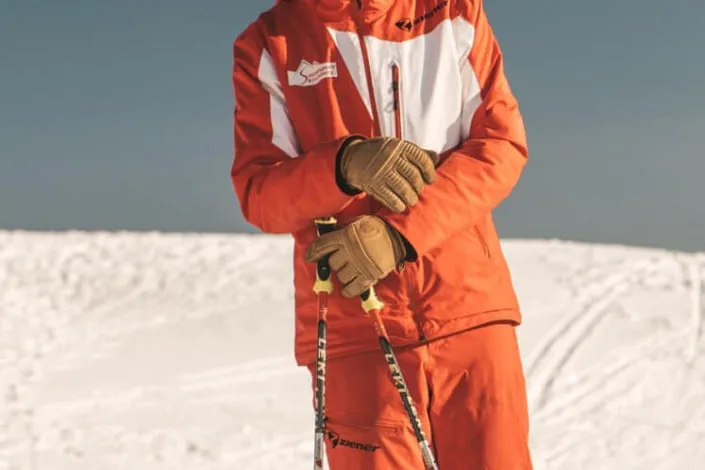 Skifahrer in orangefarbener Ausrüstung auf Schnee